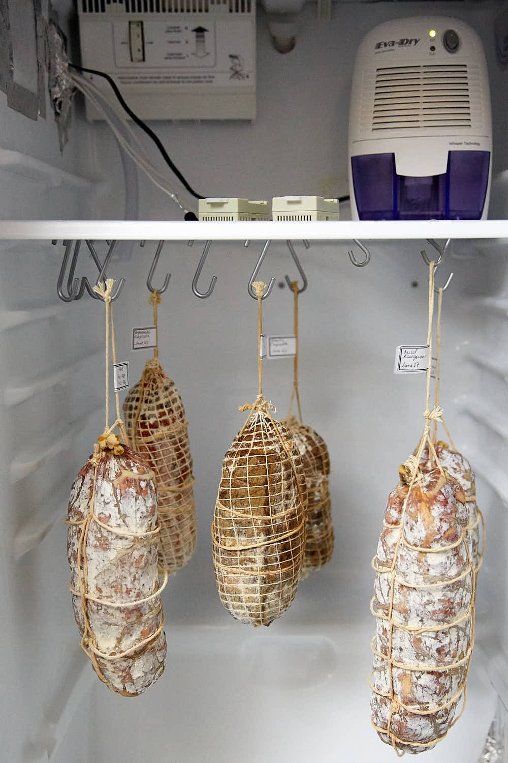 Meats hanging inside a curing chamber.