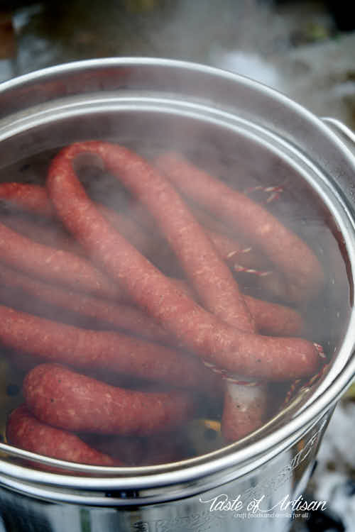 Kielbasa poaching in a pot of warm water.