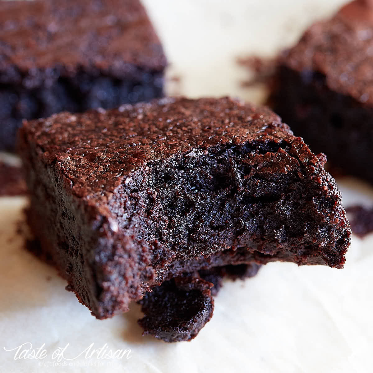 Flourless brownie, a bite taken out of, on a piece of parchment paper.