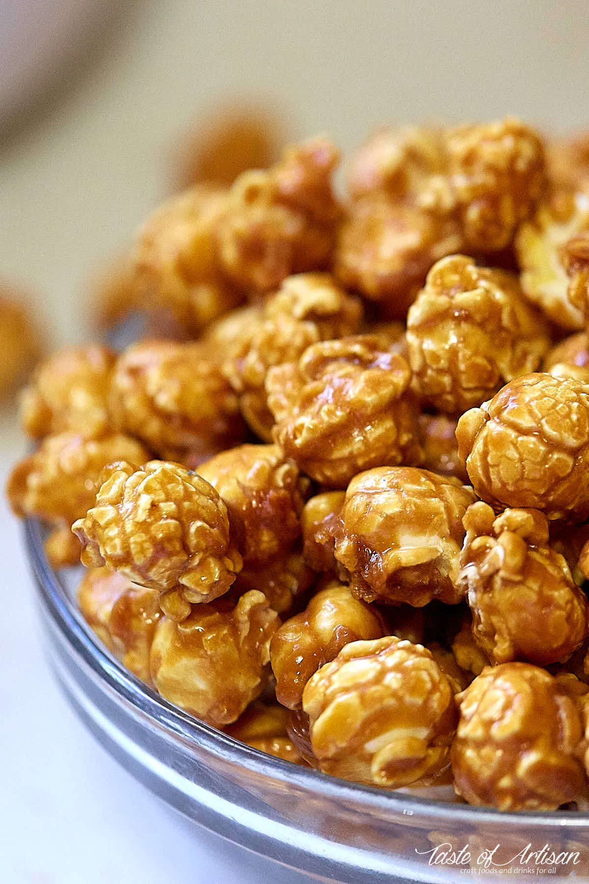 A side view of a glass bowl filled with delicious homemade caramel popcorn.