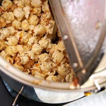 A partial view of a popcorn popper filled with mushroom popcorn just before making caramel popcorn.