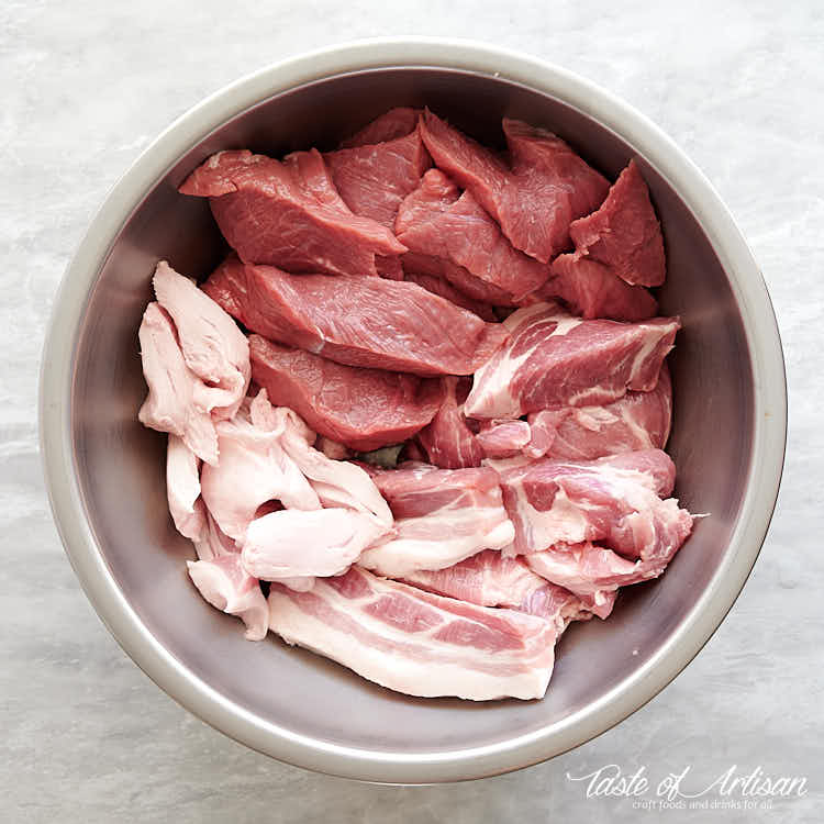 Cut up meat for bockwurst sausage in a stainless steel bowl.