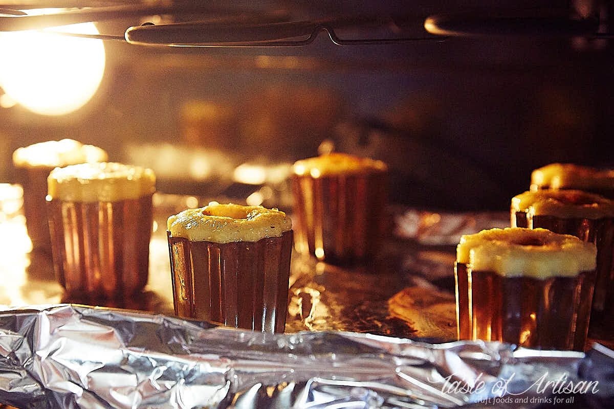 Caneles baking inside copper molds in an oven.