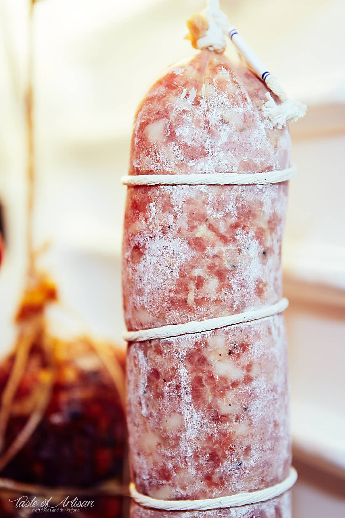 Sopressata (soppressata), covered in white mold, inside a curing chamber..