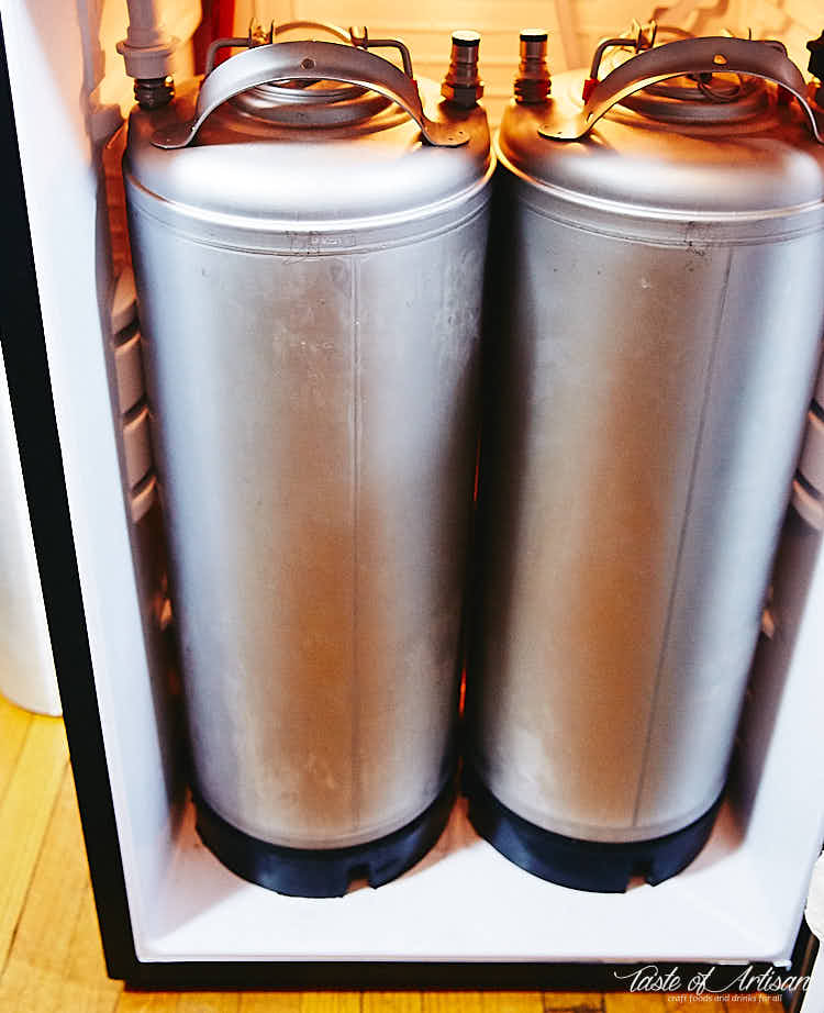 Two kegs inside a bar fridge with carbonated water.