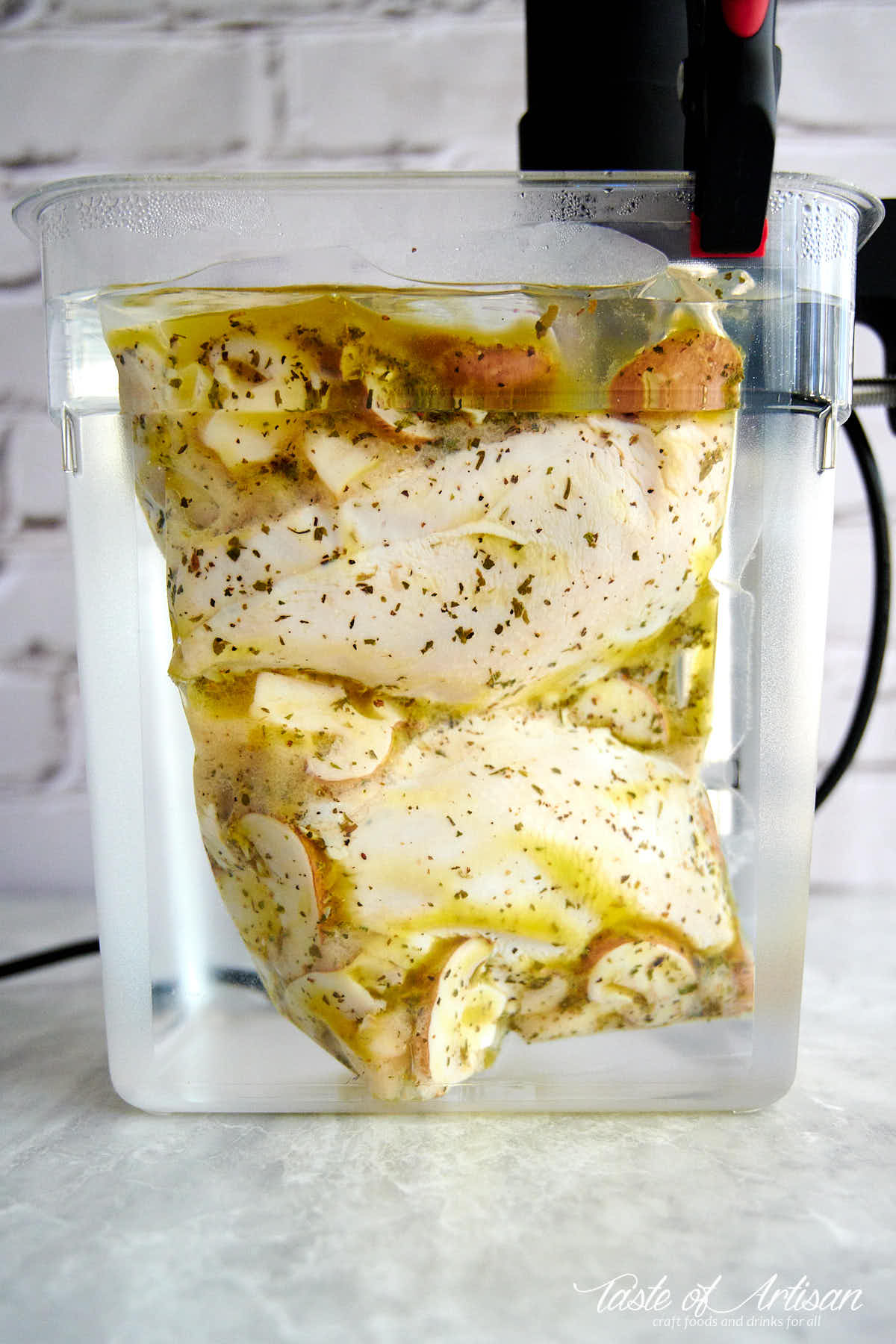 Chicken breasts inside clear water container cooking sous vide.