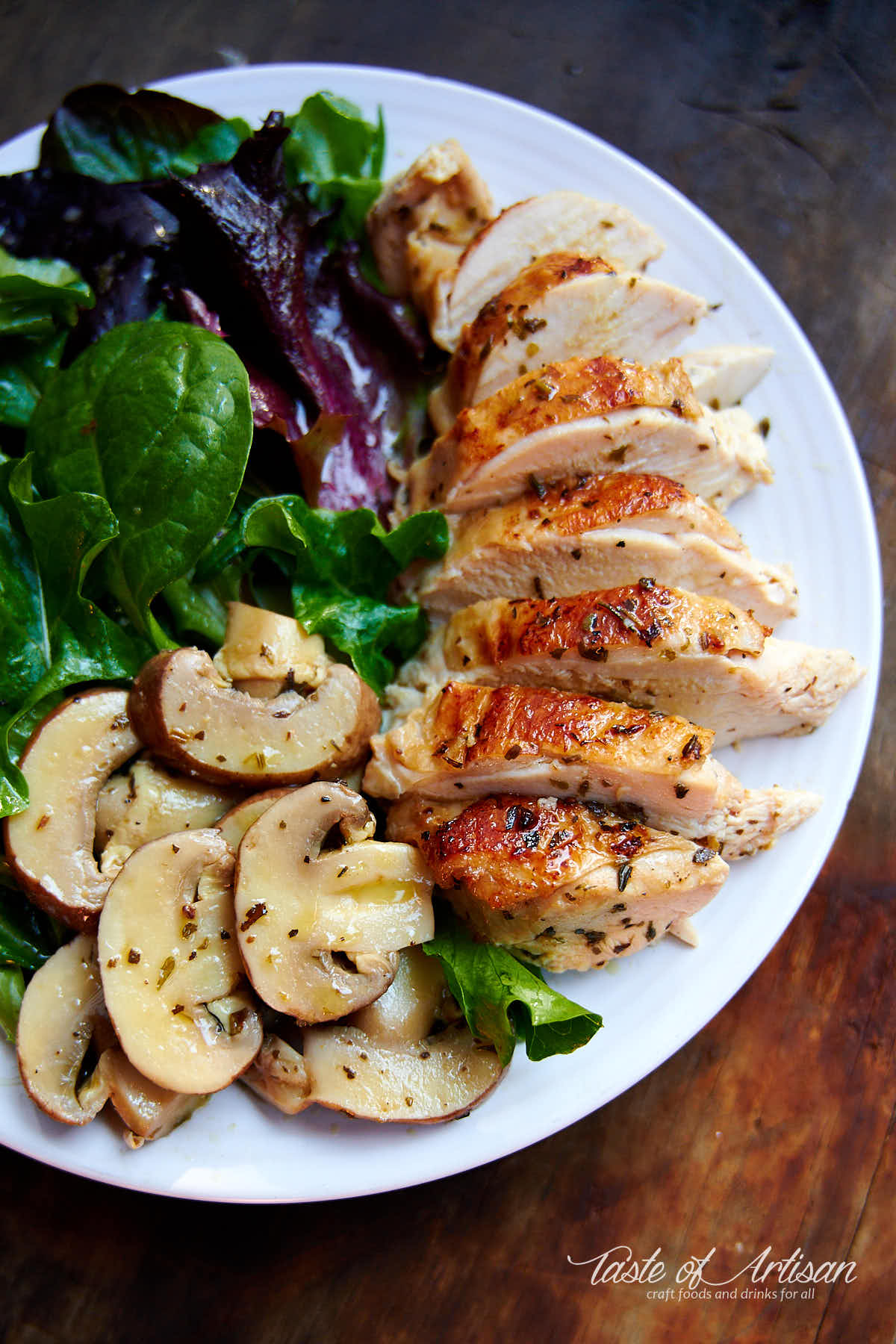 Sous vide chicken breast on a white plate with mushrooms and salad.