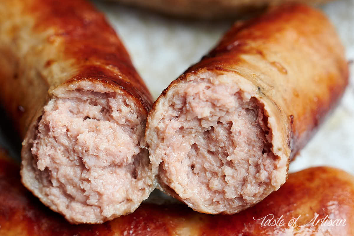 Close up of bockwurst snapped in half, showing pink, juicy meat.