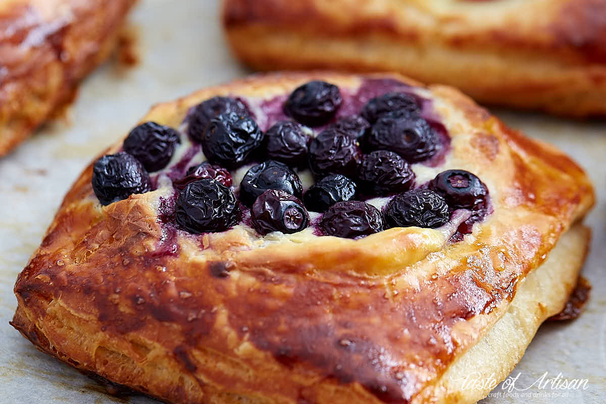 Close up of a cheese danish topped with blueberries.