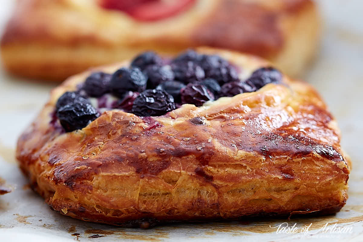 Side view of a cheese danish topped with blueberries.