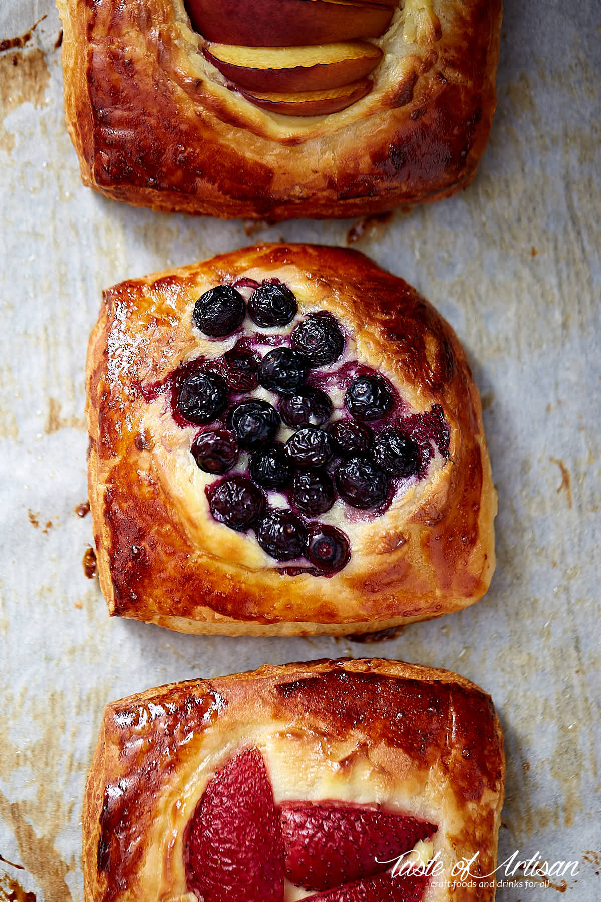 Cheese danish topped with berries on a baking sheet.