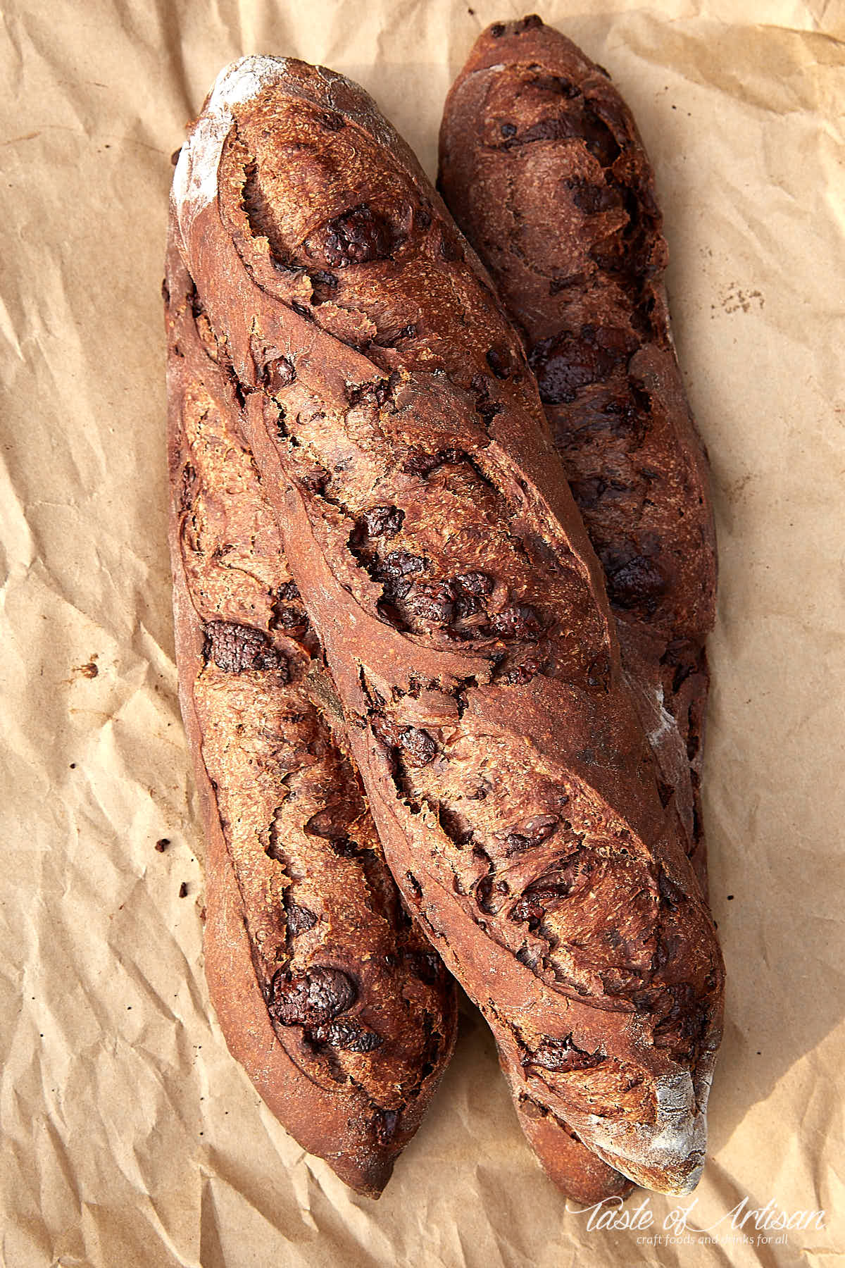 Three chocolate baguettes on a piece of brown paper.