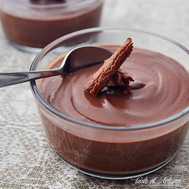 Chocolate pudding in a container with a spoon and shaved chocolate on top.