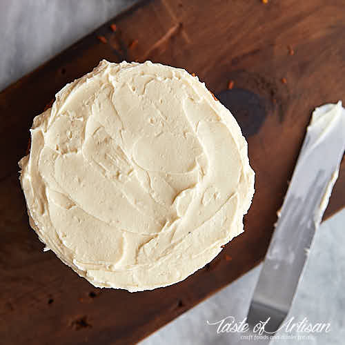 Carrot cake with cream cheese frosting spread on top.