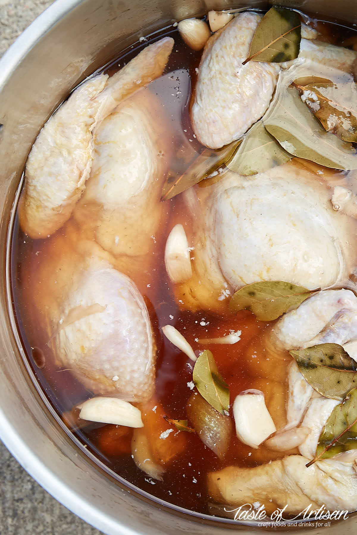 Chicken soaking in brine flavored with vegetables and spices.