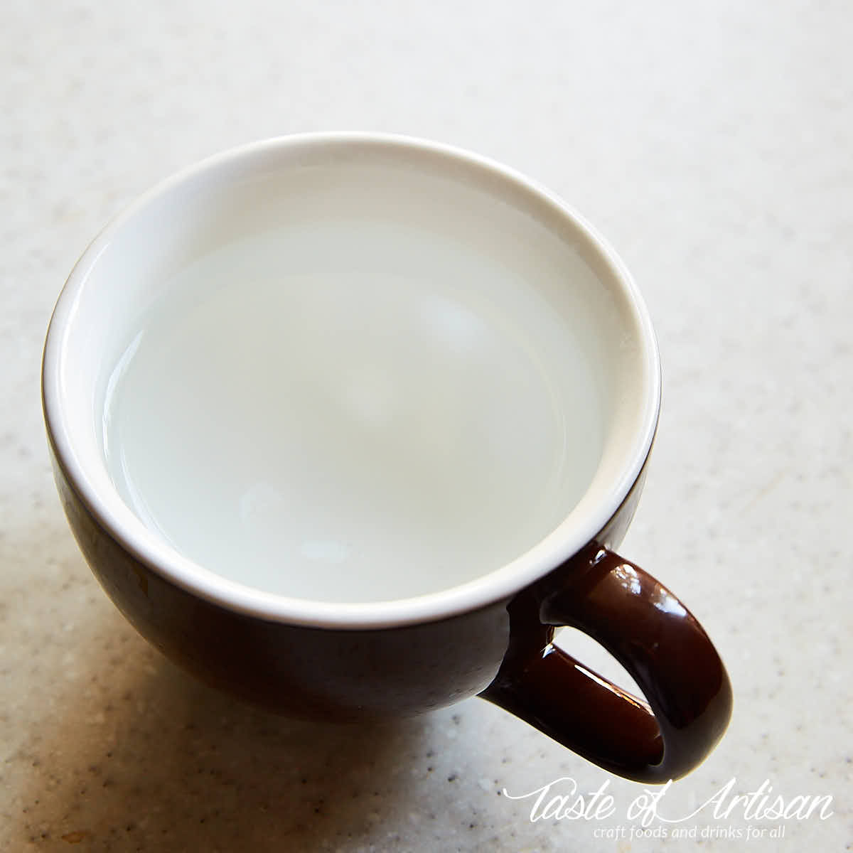 A large brown demitasse cup will with hot water.