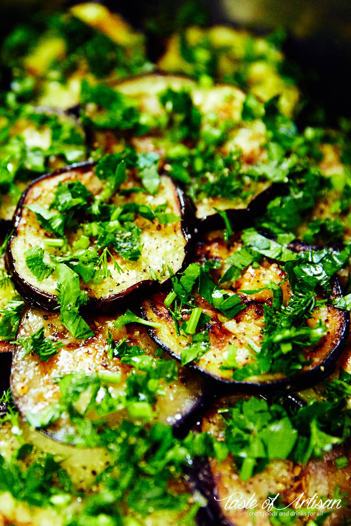 Close up of marinated eggplant slices sprinkled with chopped greens.