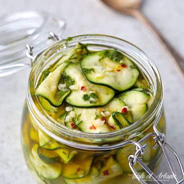 Sliced marinated zucchini in a glass jar.