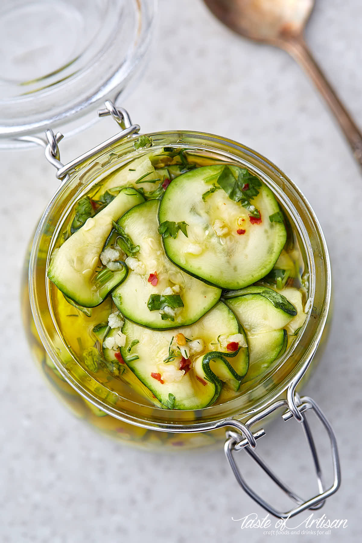 Top down view of slices of marinated zucchini in a glass jar.