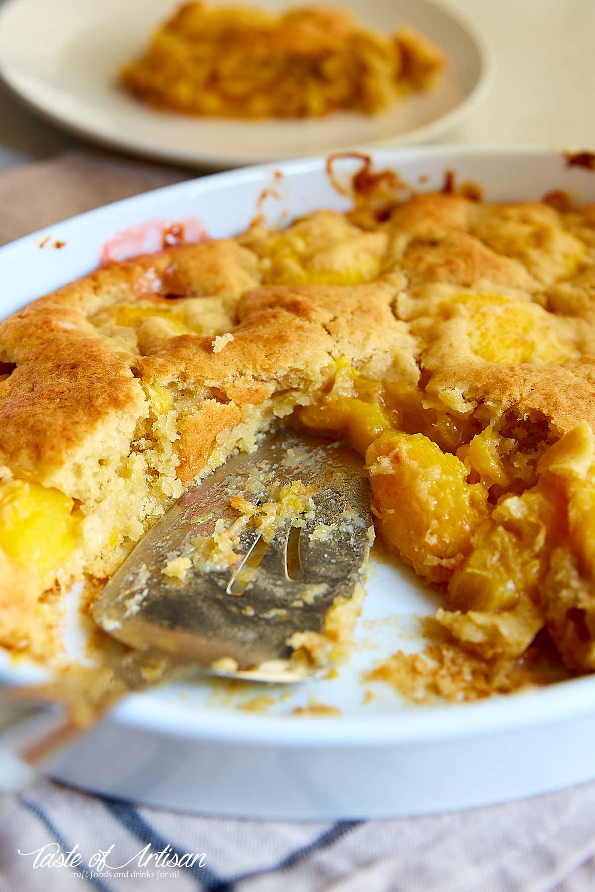 Close up of peach dump cake crumb inside a white baking dish.