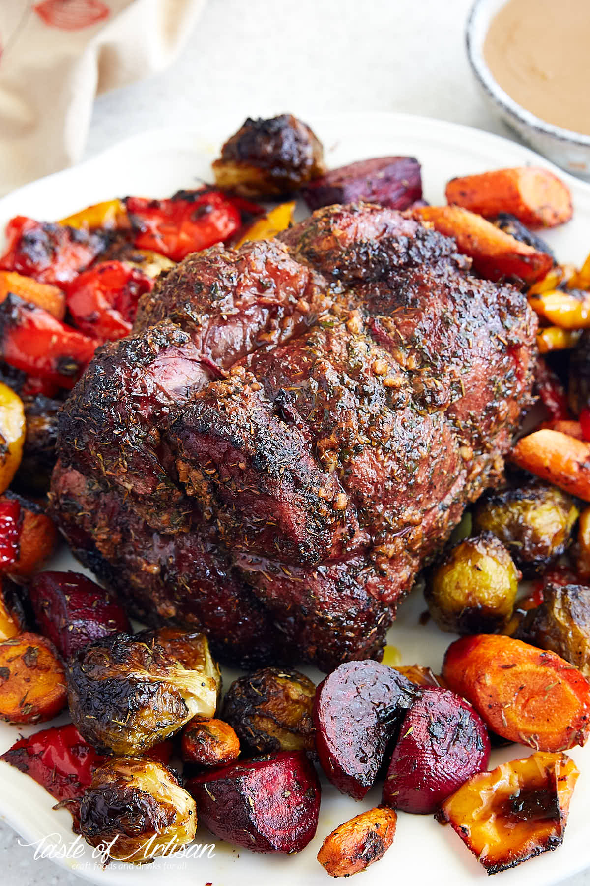 Rotisserie op round roast on a platter with roasted vegetables.