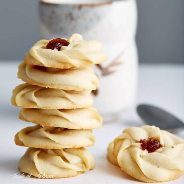 Shortbread cookies with jam on a white table.