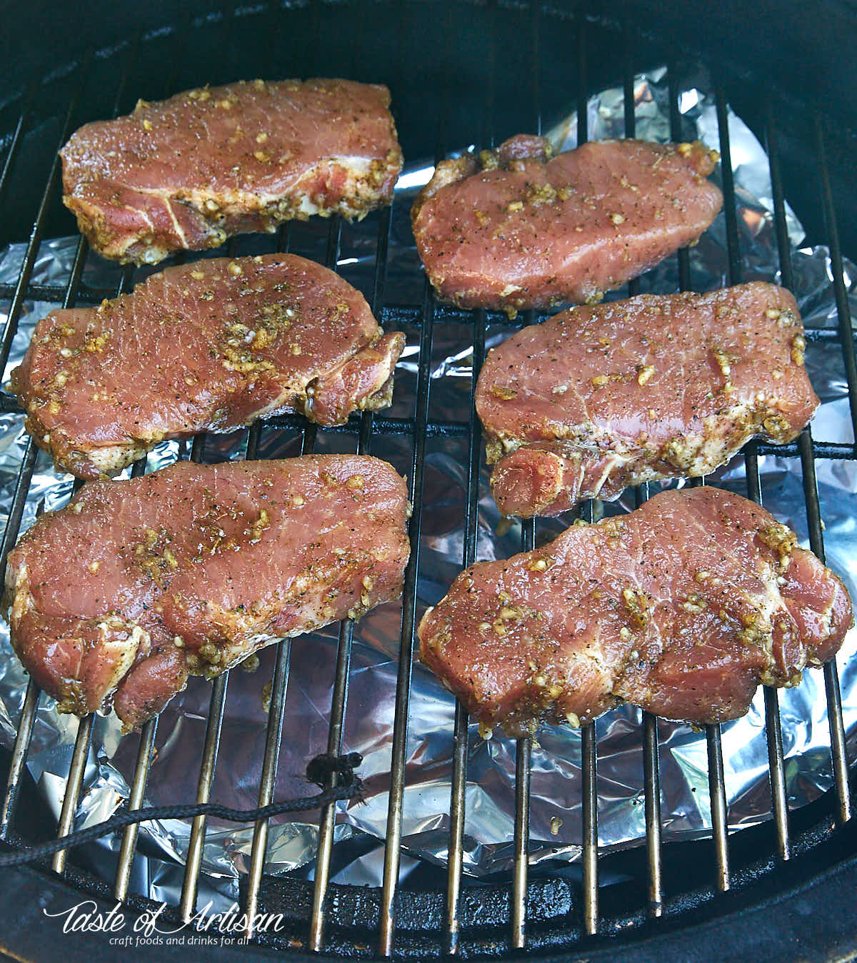 Season pork chops on the rack of a smoker.