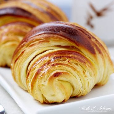 Homemade Tartine croissant on a white plate next to a coffee cup.