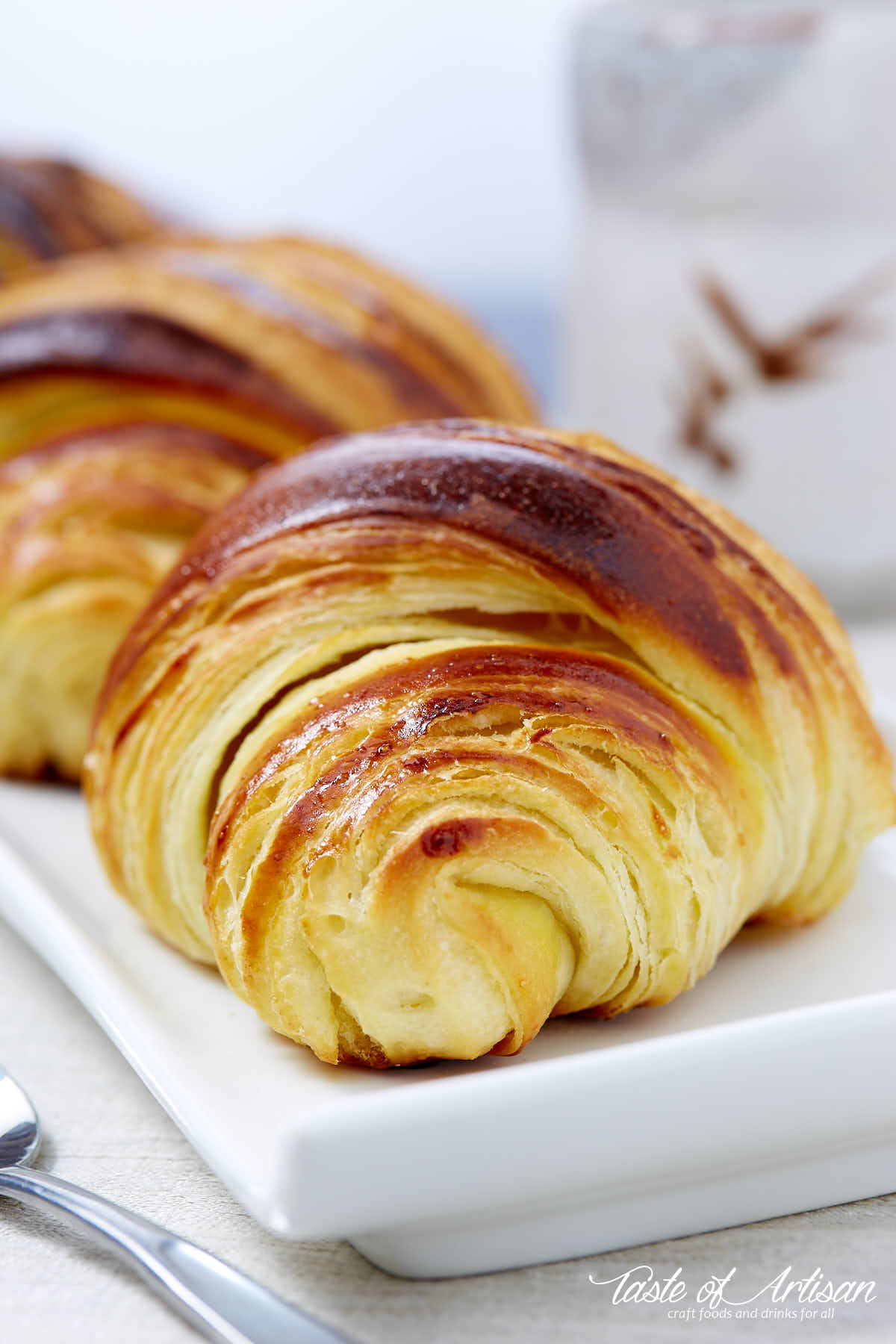 Homemade Tartine croissant on a white plate next to a coffee cup.