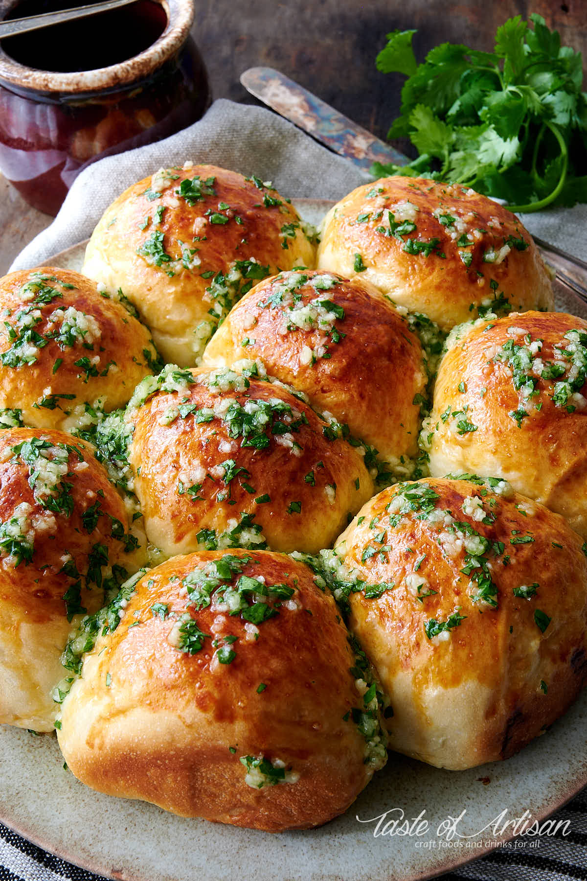 Pampushki on a plate, drizzled with garlic sauce and chopped greens.