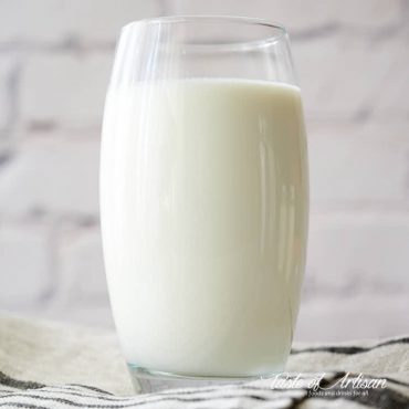 A glass of buttermilk on a a table.