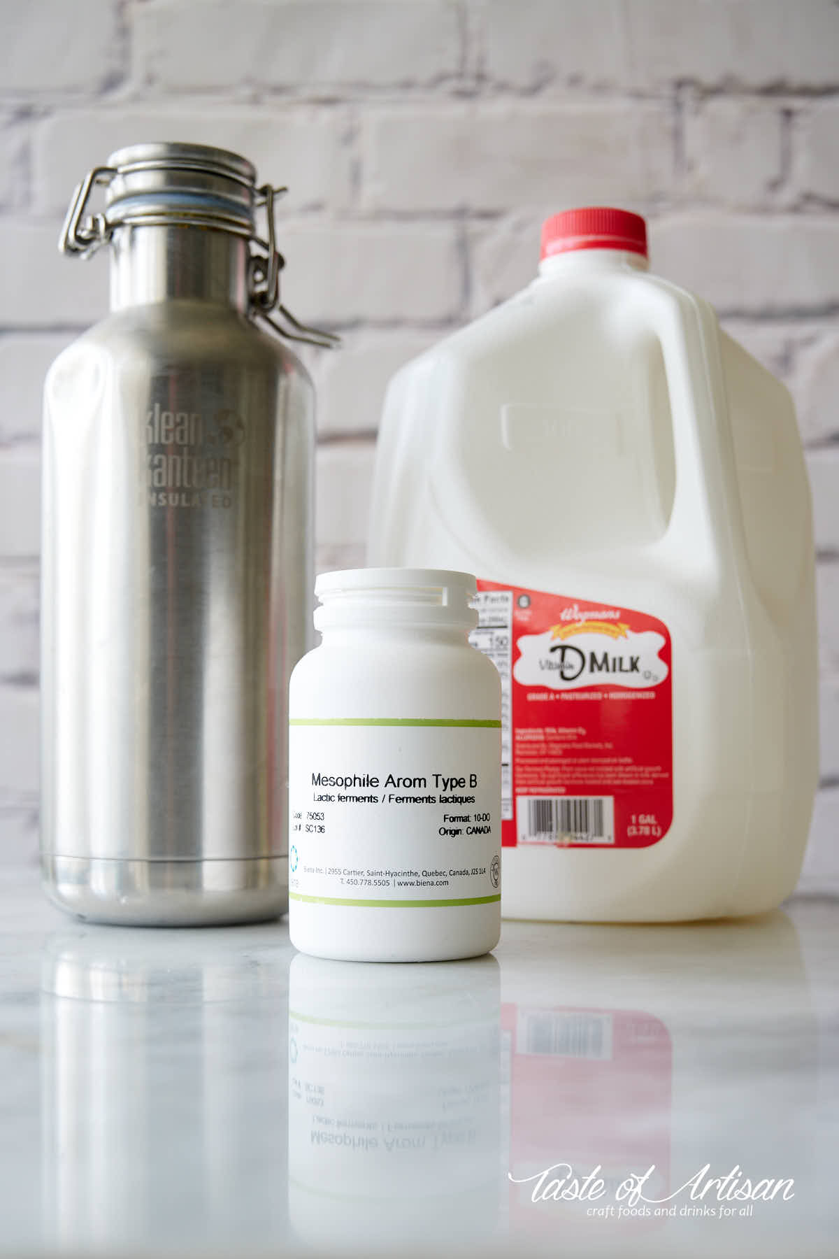 A jug of milk, mesophilic culture and thermos on a table.