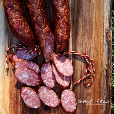 Sliced Andouille Sausage on a brown cutting board.