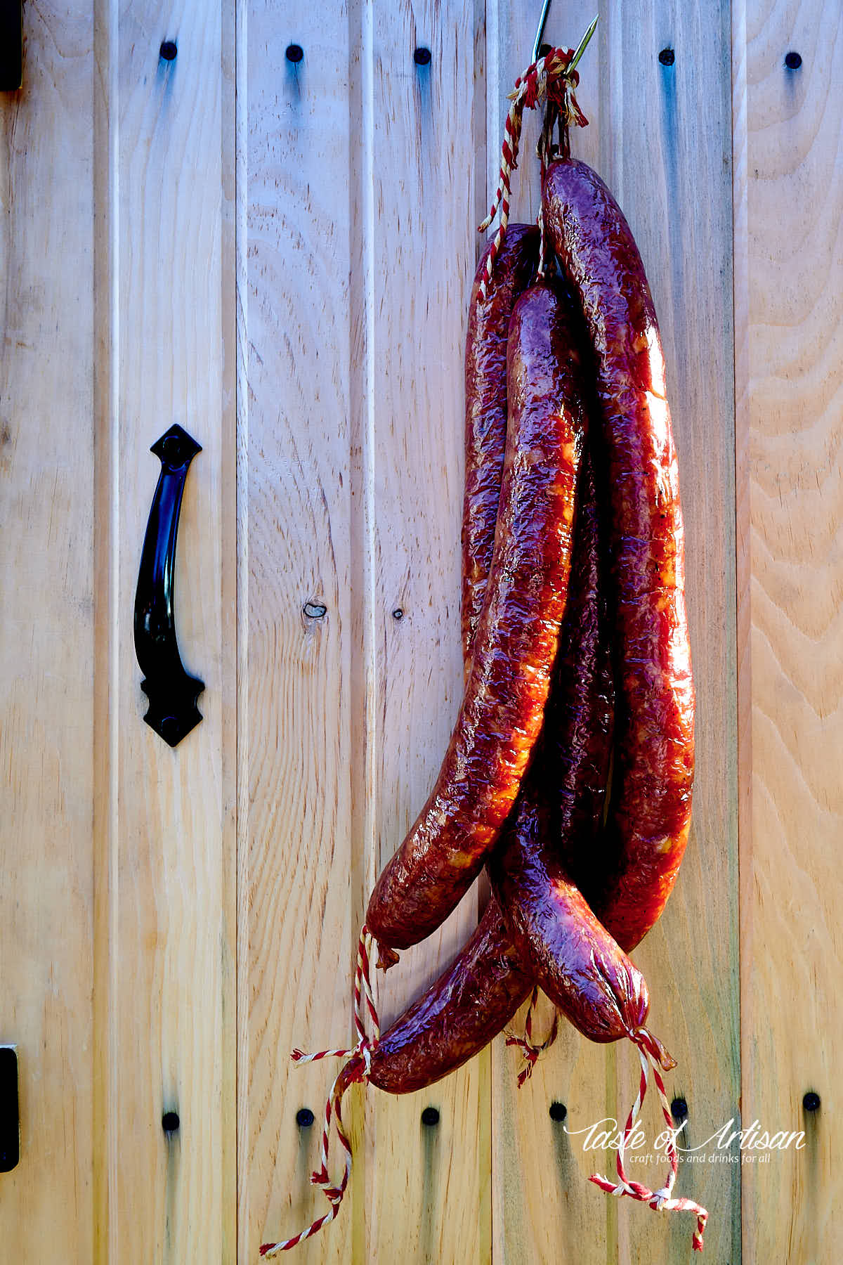 Smoked Andouille sausages hanging on the door or a smokehouse. Rich mahogany color.