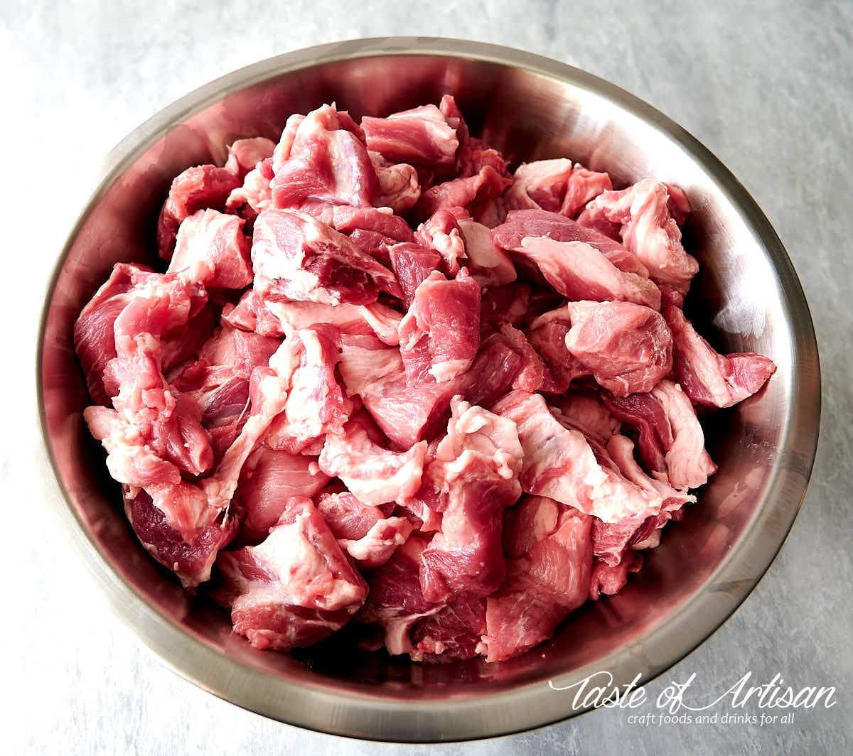 Meat chunks in a stainless bowl for making Andouille.