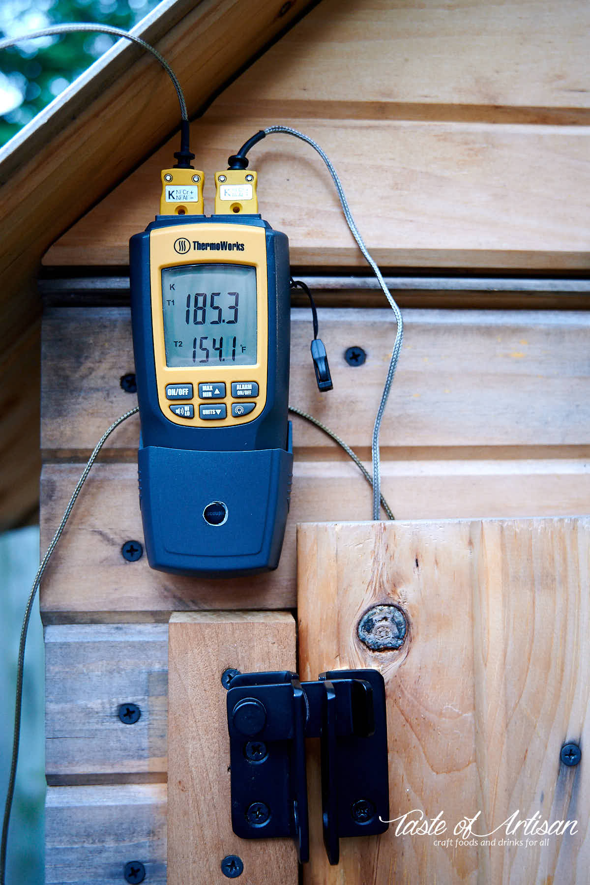 Thermometer on a smokehouse showing smokehouse temperature and internal Andouille sausage temperature.