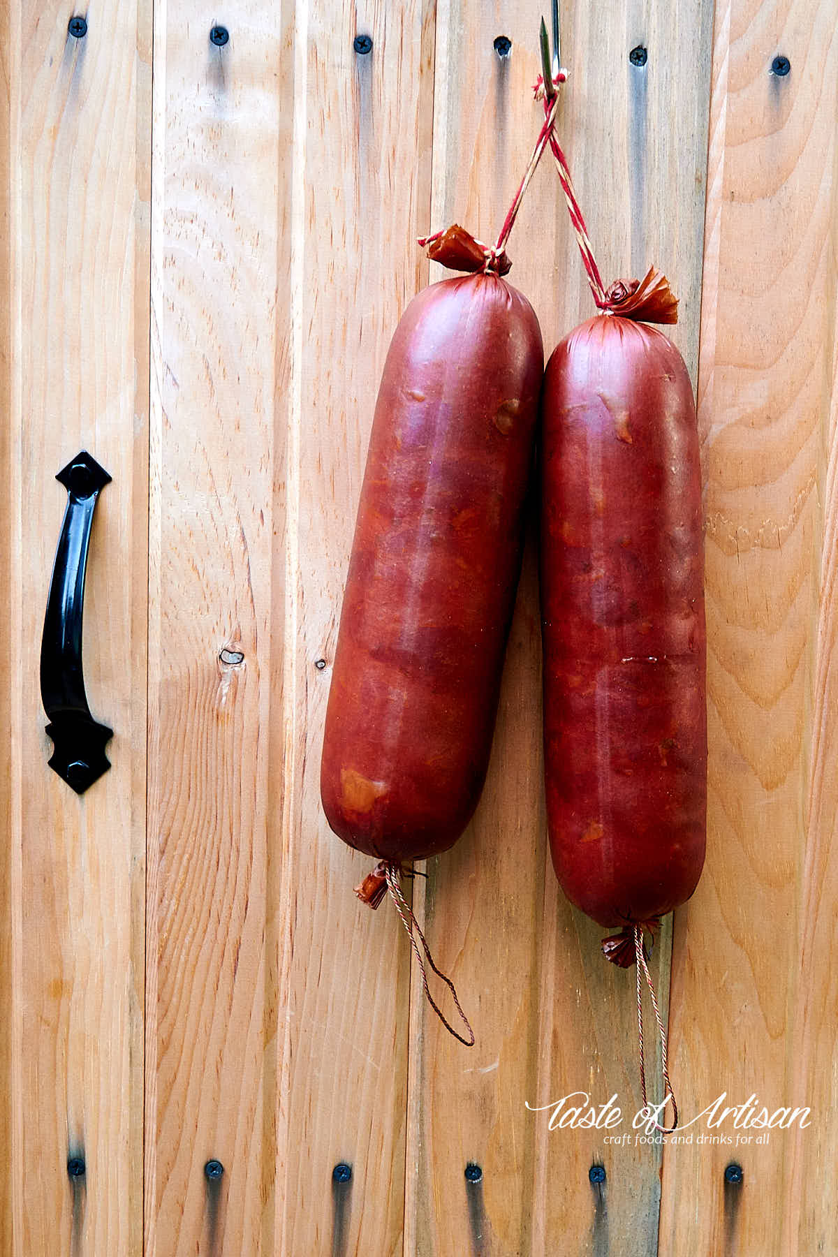 Krakow sausage hanging from the door of a smokehouse.