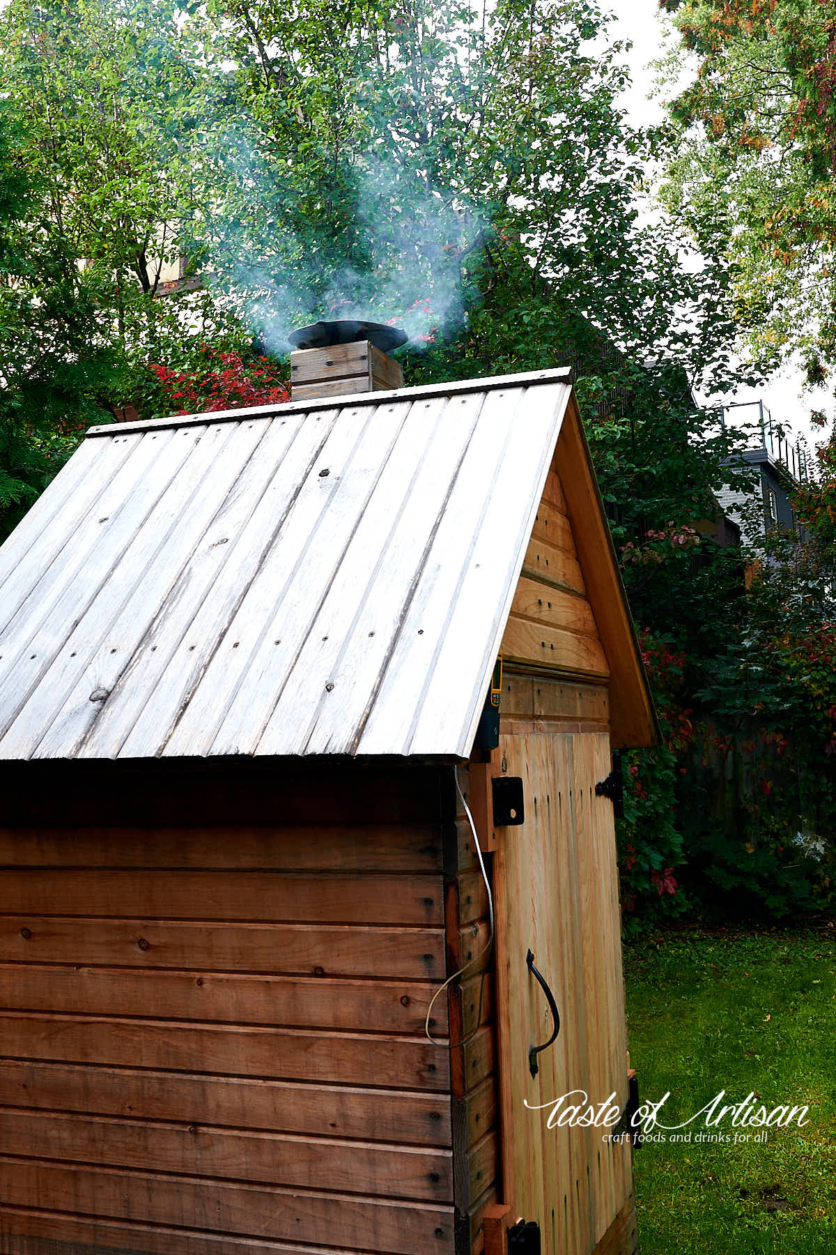 Thin blue smoke coming out of chimney of a smokehouse.