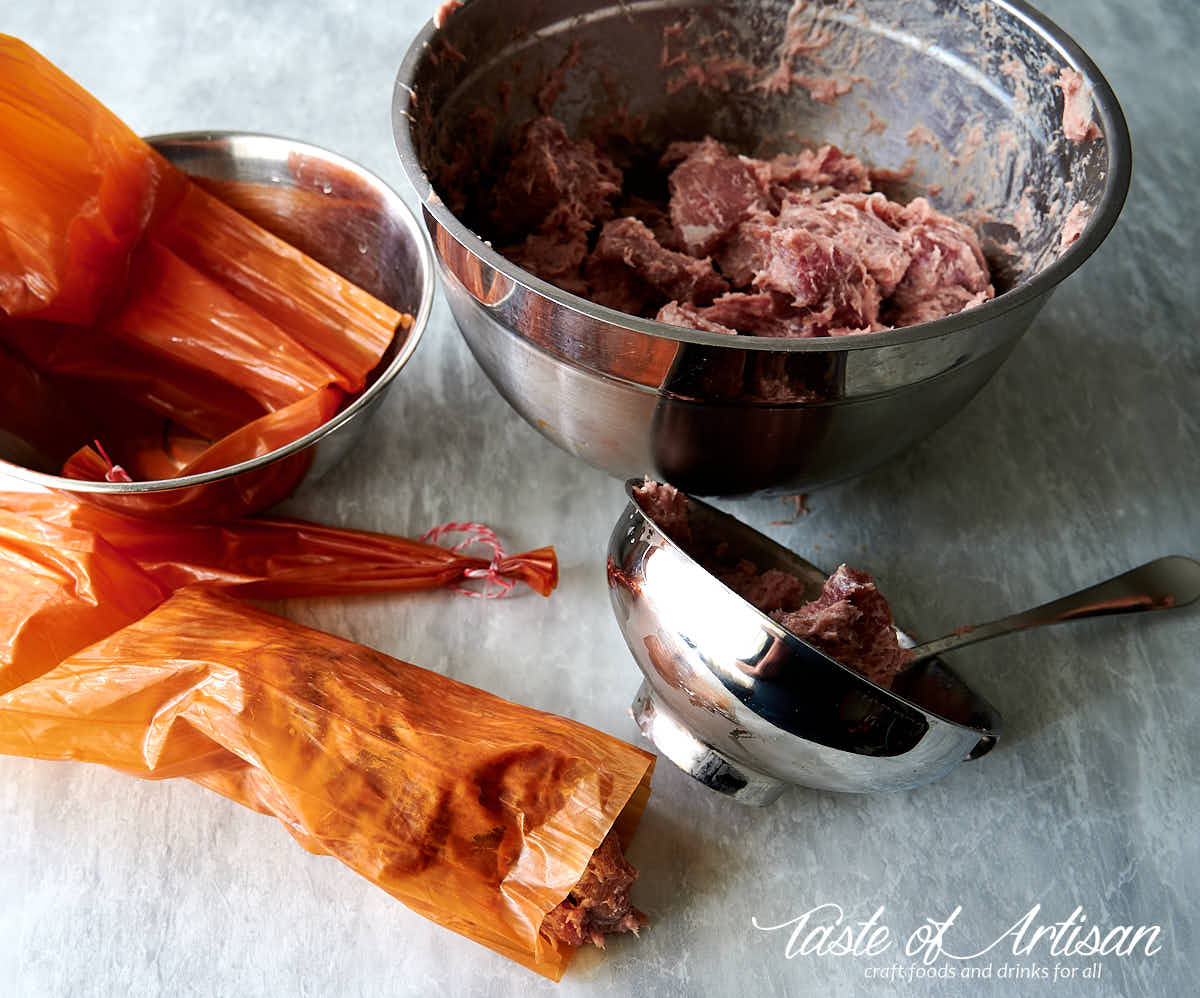 Stuffing krakow sausages using a stainless steel funnel.