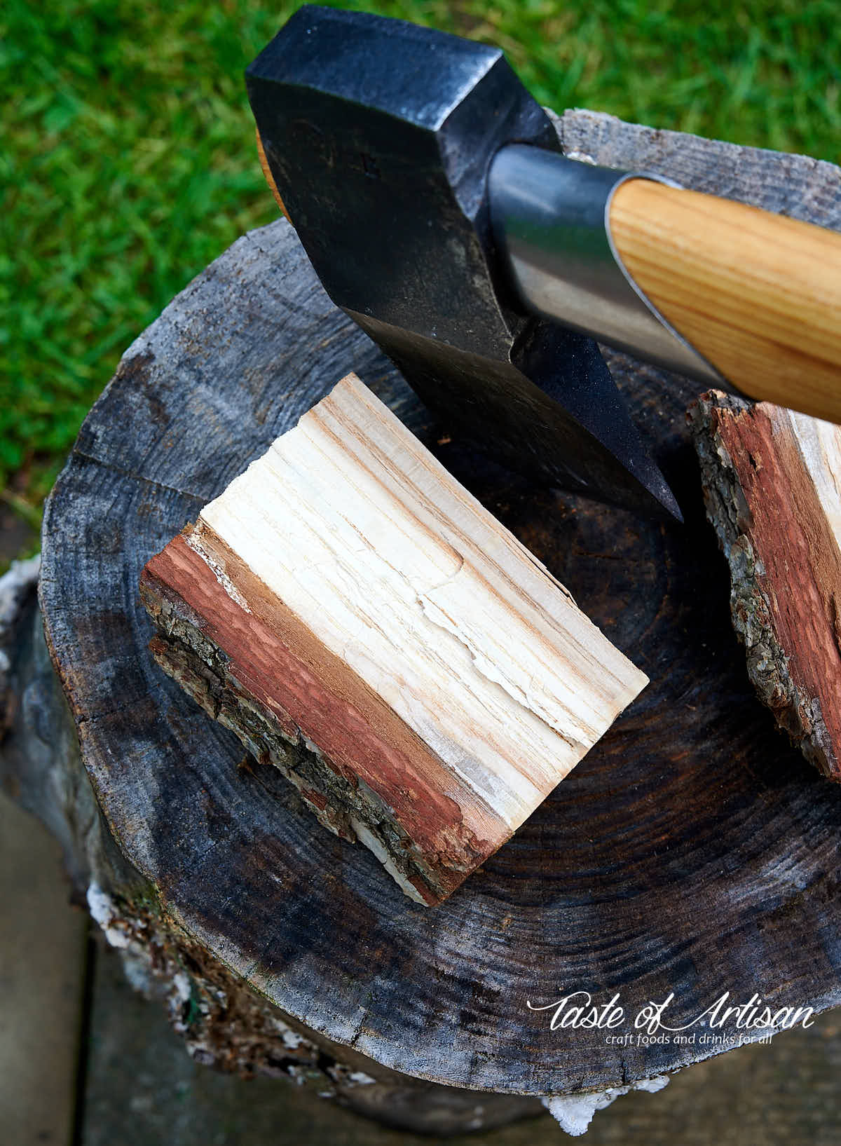 Splitting oak wood with an axe on a tree stump.