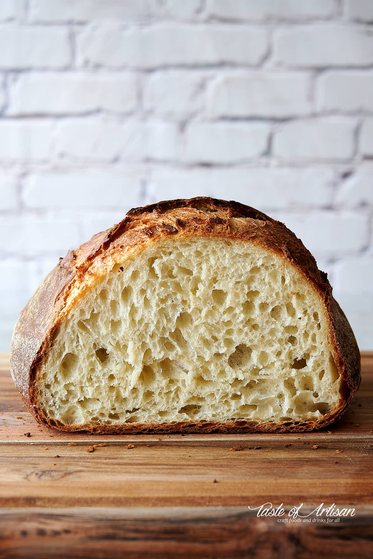 No-knead bread, cut in half, cut side facing viewer, on a cutting board.
