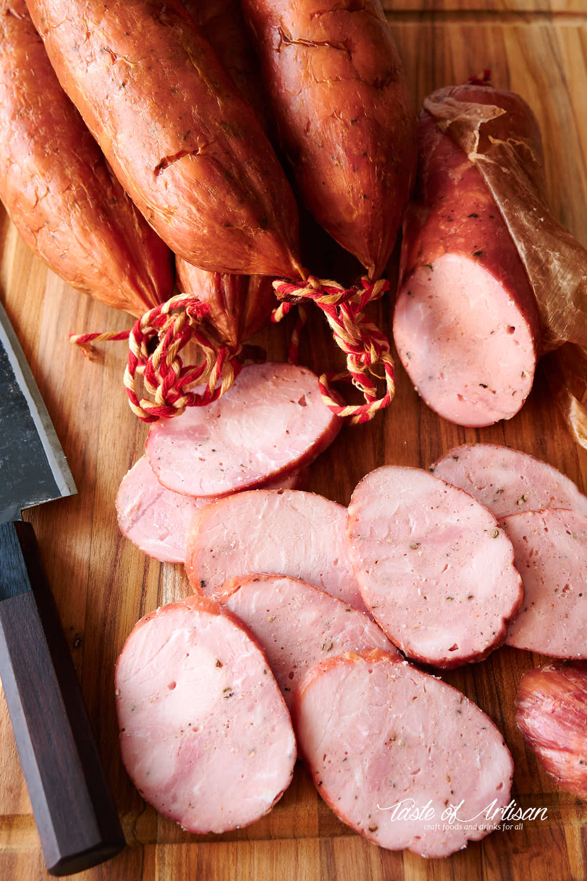 Smoked kielbasa, whole links and sliced on a cutting board.