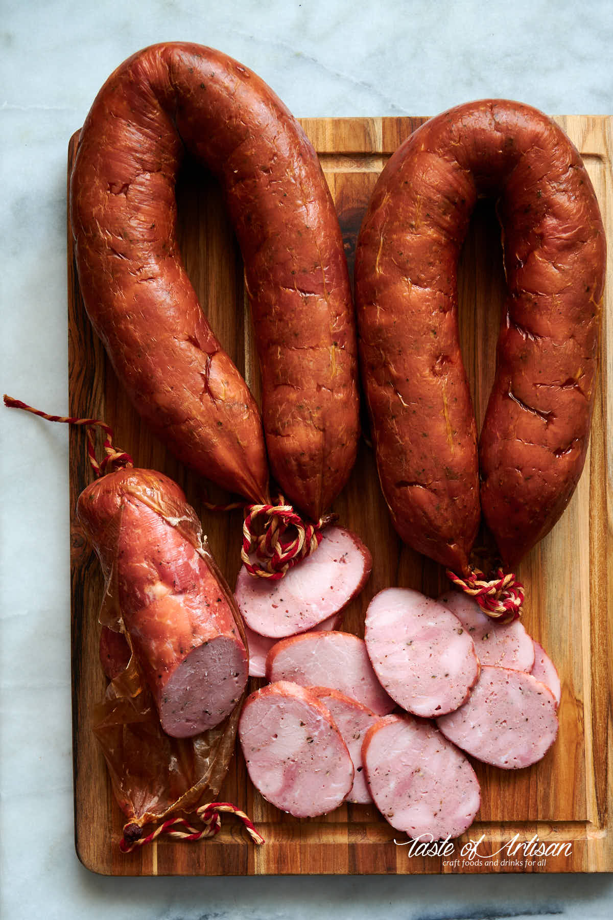 Smoked kielbasa, whole links and sliced on a cutting board.