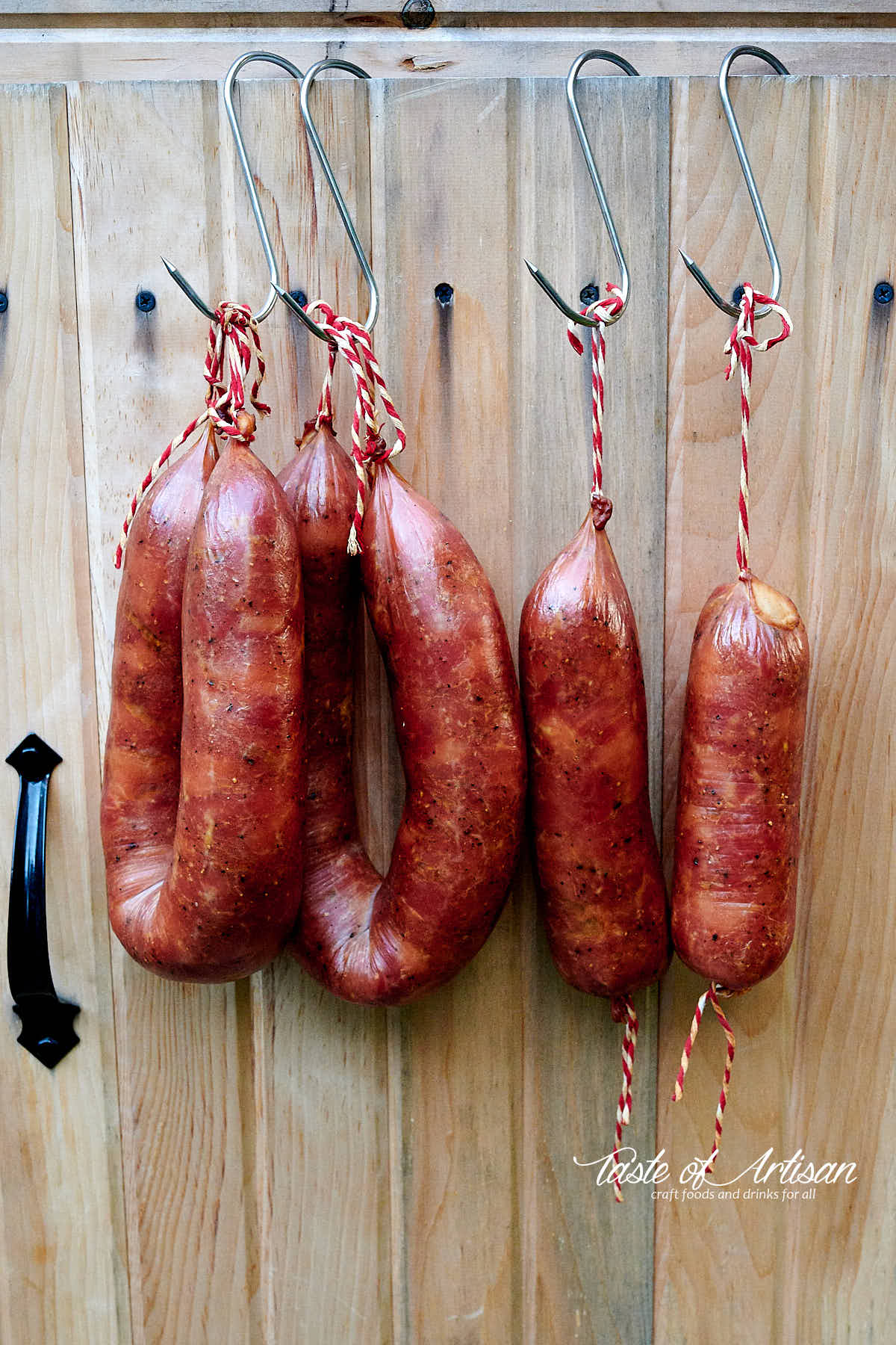 Smoked kielbasa rings hanging on the door of a smokehouse.