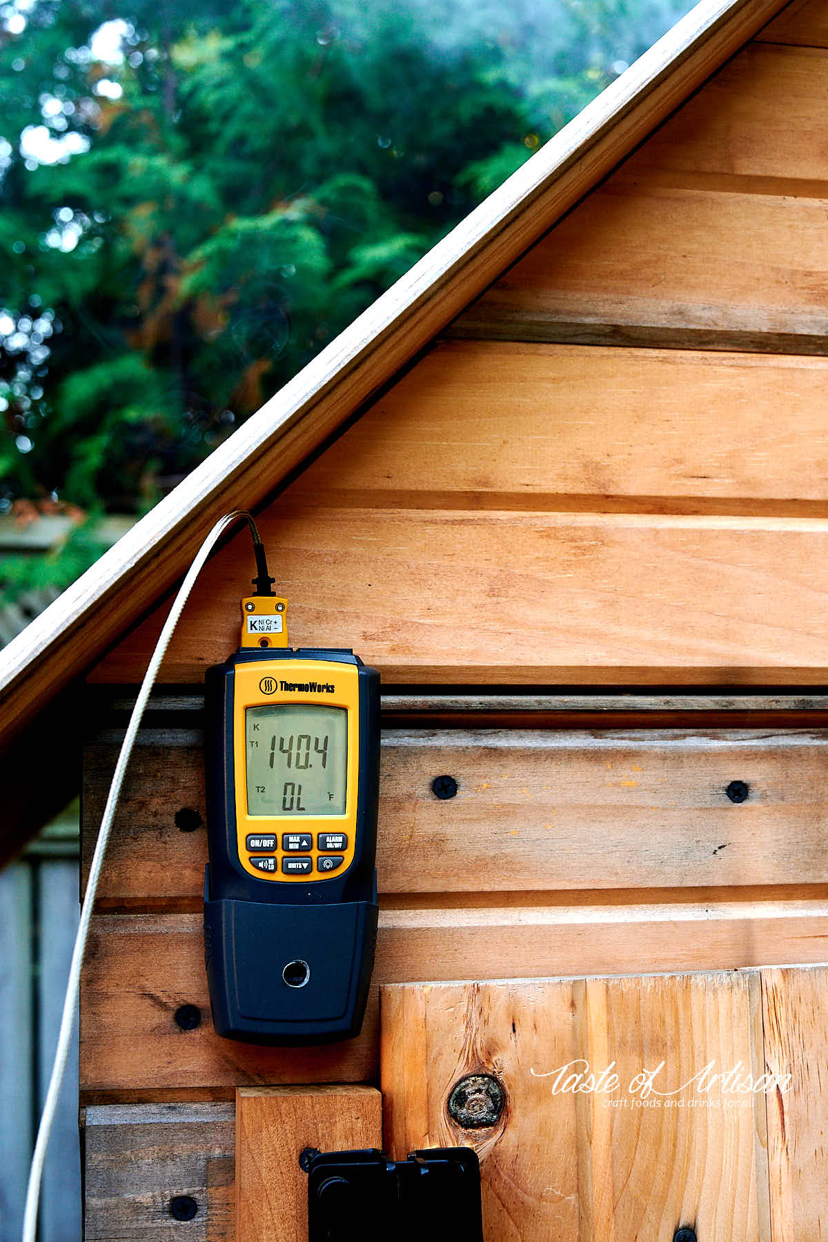 Thermometer showing smokehouse temperature.