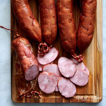 Sliced smoked kielbasa on a cutting board.