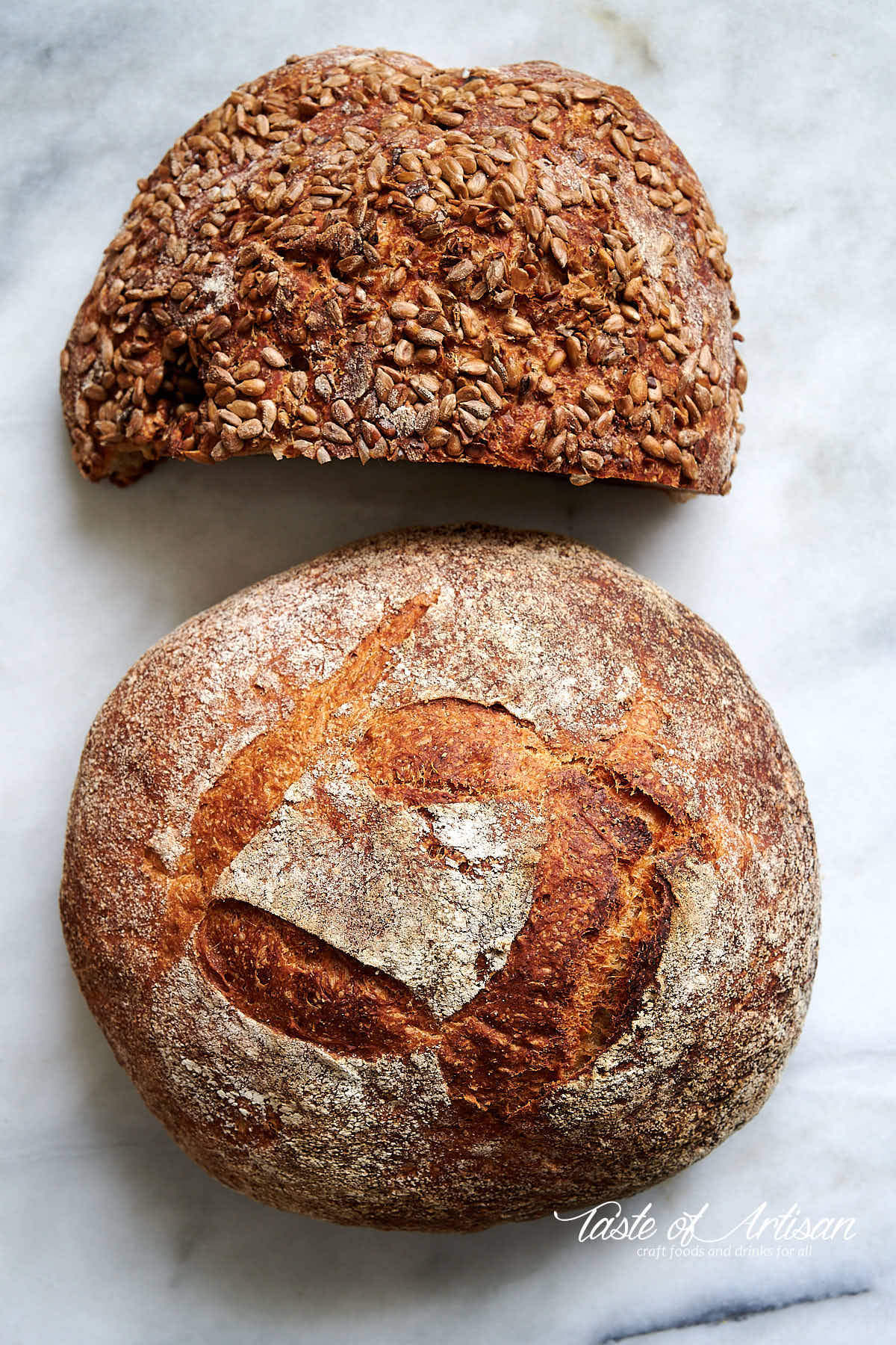 Whole what and rye no knead bread loaves on a marble table.