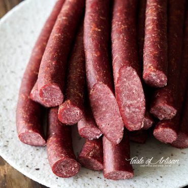 Smoked beef sticks on a speckled plate.