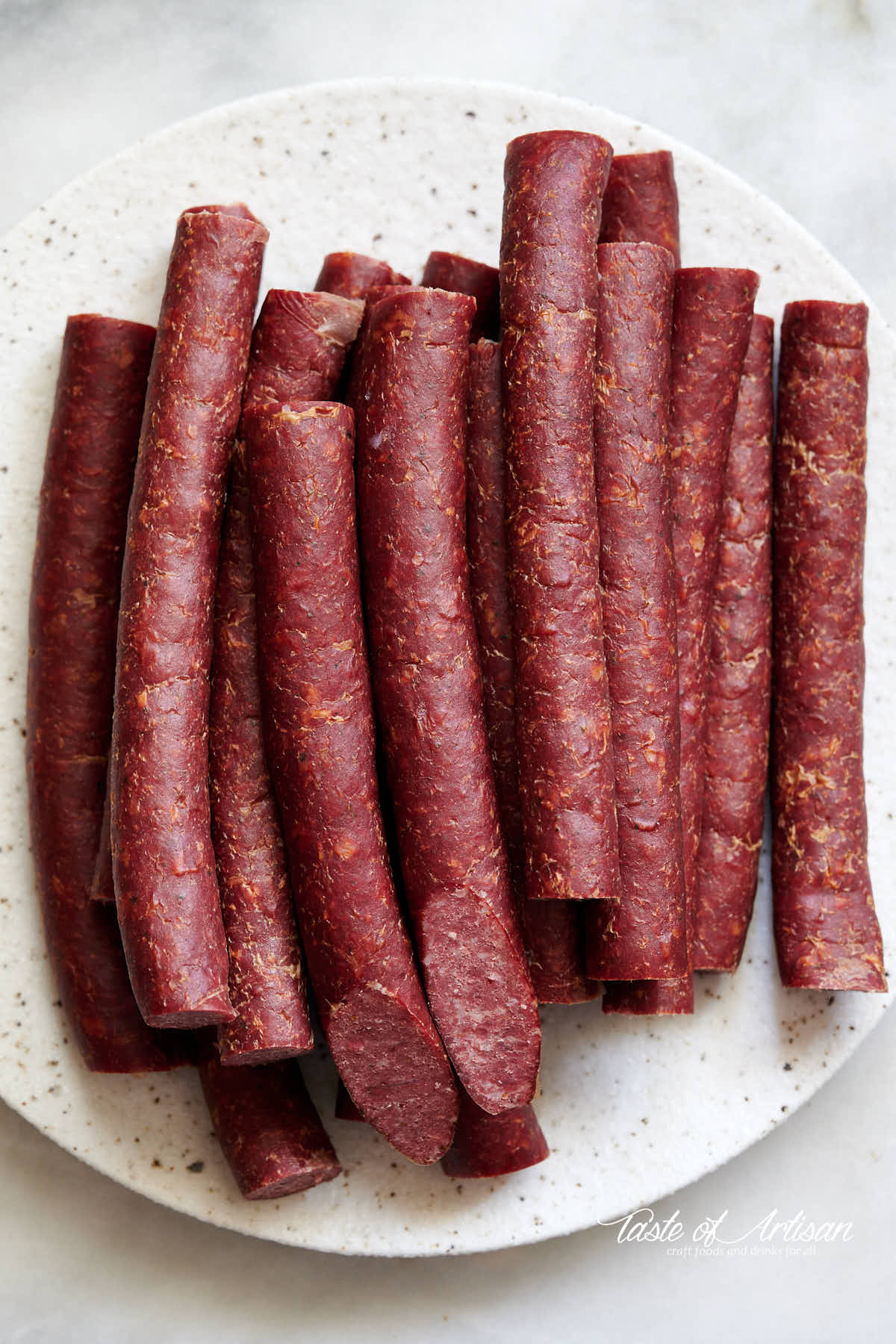 Top down view of mahogany color smoked beef sticks on a marble table.