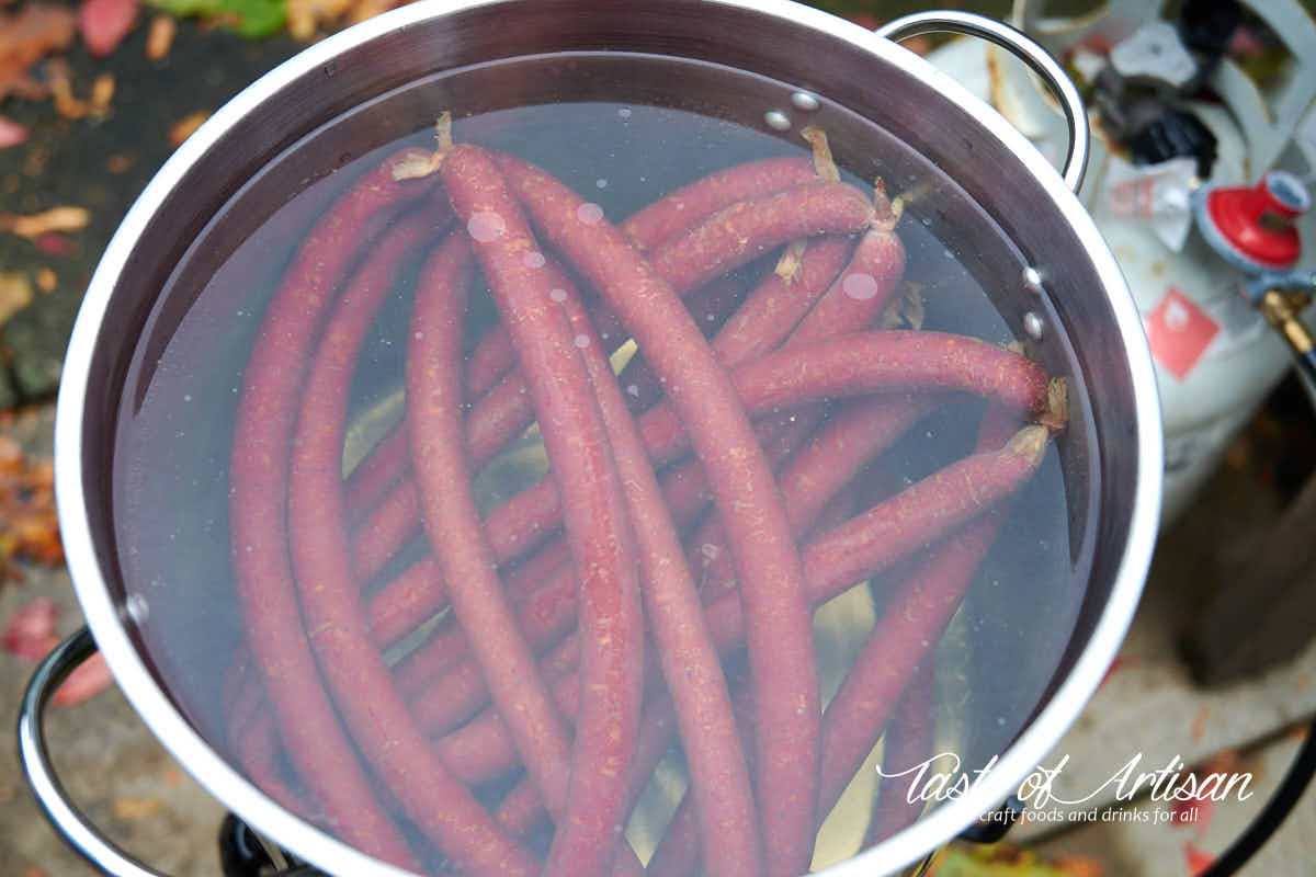 Smoked beef sticks poaching in hot water.